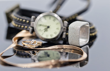 Elegant gold and silver ring and chain lie on the background of women's watches