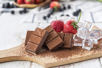 Chocolate with fresh berries on wooden table