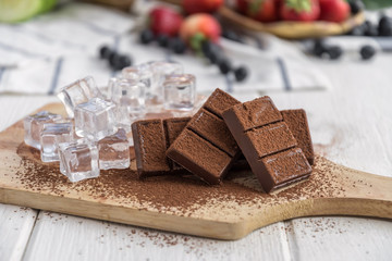 Chocolate with fresh berries on wooden table