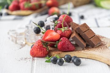 Chocolate with fresh berries on wooden table