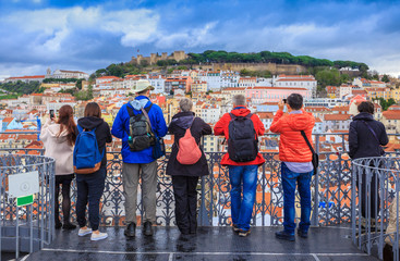 Group of tourists watching the cityscape of Lisbon and taking pictures to Sao Jorge castle in Portugal - obrazy, fototapety, plakaty