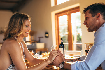 Loving young couple holding hands at dining table © Jacob Lund