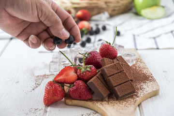 Chocolate with fresh berries on wooden table