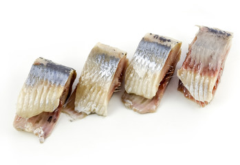 Slices of salted herring on the plate on white background.