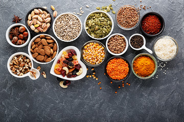 Composition with assortment of superfood products in bowls on gray background, top view