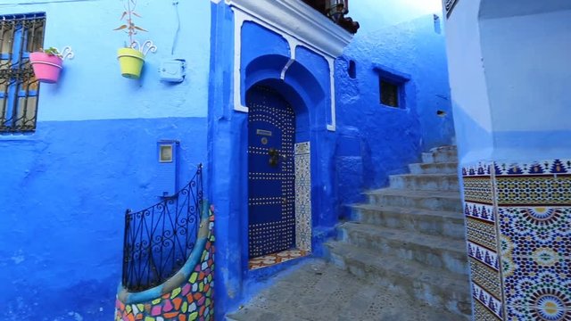 Panorama of traditional old blue street with color pots inside Medina of Chefchaouen, Morocco
