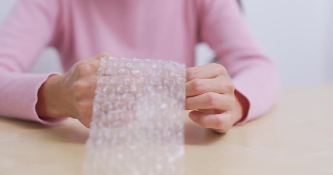 Woman play with bubble wrap at home