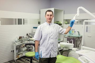 Male dentist standing over medical office background. Healthcare, profession, stomatology and medicine concept