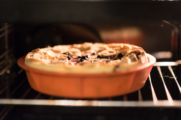 Raw vegan sweet tart, pie or cake with blueberries currants, coconut, dates, bananas, oil, cocoa powder and cashew cream on a silicone plate in the oven . Organic product.