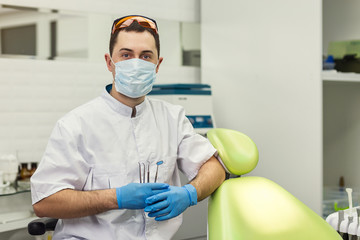 Male dentist standing over medical office background. Healthcare, profession, stomatology and medicine concept