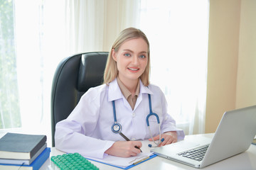 Doctor Concept. Smiling doctor posing in the office. Young doctor is wearing a stethoscope. medical staff on the hospital background. The doctors are happy to work.