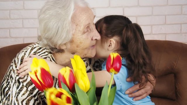 Happy old age. A child gives an elderly woman flowers.