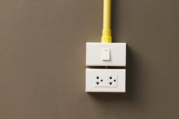 Plug and socket installed on brown wall