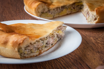 Triangular piece of pie is taken out of pie on a separate white plate