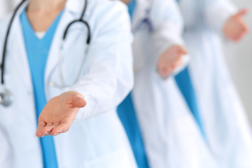 Group of medicine doctors offering helping hand  for shaking hand or saving life closeup. Partnership and trust concept in health care or medical cure 