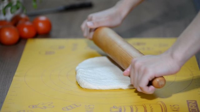 Housewife rolls pizza dough