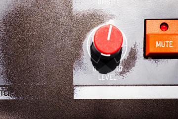 Close-up shot of level knob with numbered label with mute button on worn metal board with faded...