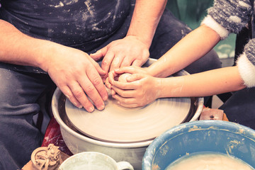 Little child learns how to sculpt a ceramic plate on a potter's wheel. Close-up of a child's hand.