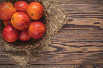 Blood orange fruit in a wicker basket on dark wooden table.