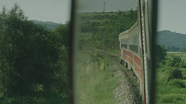 A shot of a old red and white train.Shot through a rearview mirror.