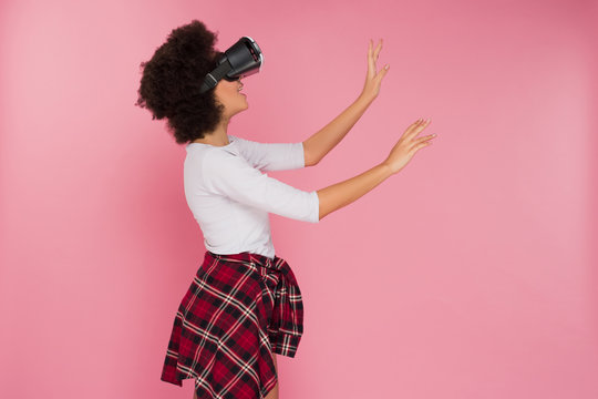 Chilling out! Beautiful cheerful African American young woman chilling out and touching the unreal world, while seeing it through 3D goggles.