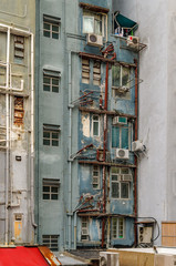 Fototapeta na wymiar Heruntergekommenes Hochhaus mit rostigen Rohrleitungen in den Hongkonger Mid-Levels