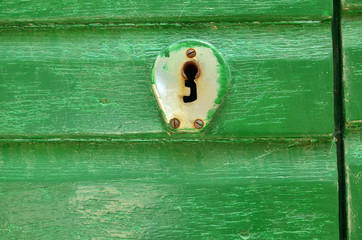 Close-up of a door lock in vintage style on a green wooden door