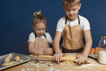 Picture of blonde 7 year old boy with hair knot helping his elderly brother to bake cookies at...