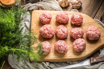 Raw meatballs on the wooden cutting board.