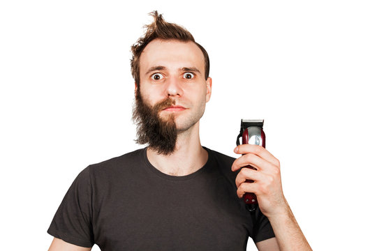 Man with half-shaved beard surprised with wide eyes holding hair clipper. Isolated on white.