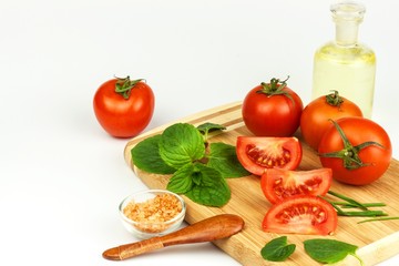 Tomatoes and herbs on a kitchen board. Preparation of healthy food. Raw vegetables. On a white background.