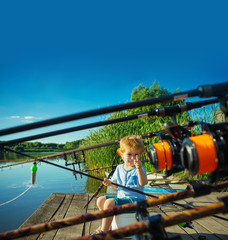 Picturesque scene of cute little boy fishing from wooden dock