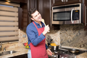 Handsome young man singing in the kitchen