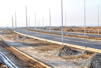 Fototapeta na wymiar Under construction road in the city with lighting poles