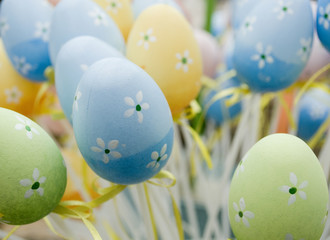 small easter eggs, colored green, orange, light blue, pink, painted with small spring flowers, yellow ribbon, religious holidays, background, april, italy