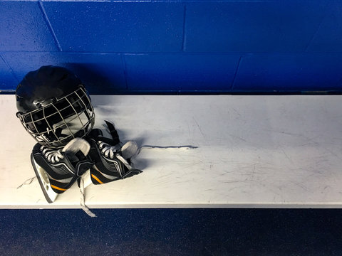 Top view of kid hockey skates and helmet in white bench in locker room with copy space 