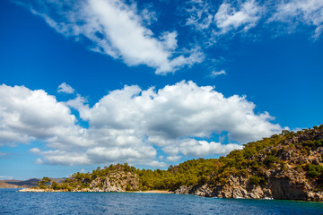 Naklejka premium Rocky coast with trees in the Aegean Sea. Big beautiful white clouds