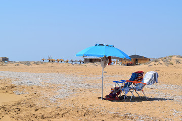 isolated beach umbrella and deck chairs on the beach in summer