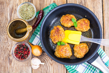 Frying pan with fried cutlets on wooden table