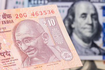 10 indian rupee  with hundred dollar bill on background