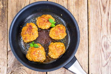 Frying pan with fried cutlets on wooden table