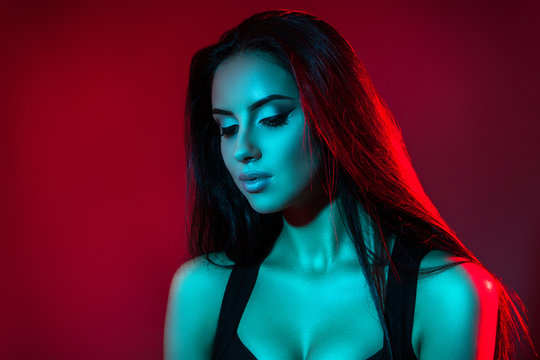 Studio creative portrait of beautiful girl model. Brunette in red and blue light of.