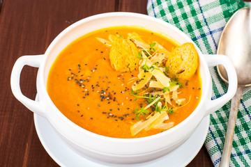 Pumpkin carrot cream soup with parmesan and green shoots of watercress