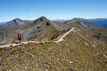 A hiker walking along the ridge line trail of the Kepler Track in New Zealand.