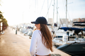 Attractive young woman posing with a cap in marina in the sunset
