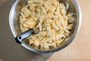 Chopped peeled pears and a knife in a metal bowl