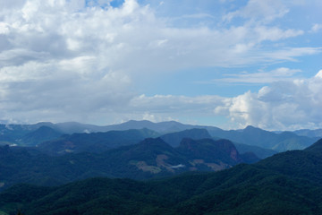 Naklejka premium Amazing wild nature view of layer of mountain forest landscape with cloudy sky at winter season. Natural green scenery of cloud and mountain slopes background.