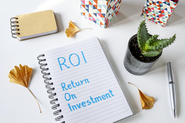 ROI Return On Investment written in notebook on white table