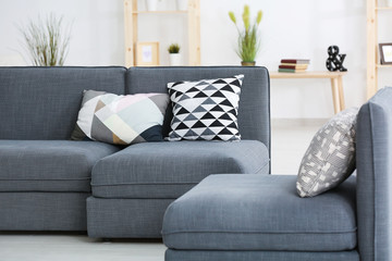 Modern grey sofa with different pillows in living room