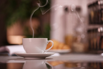 Cup of hot coffee on blurred background